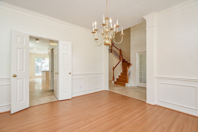 empty room with a chandelier, hardwood / wood-style floors, and crown molding