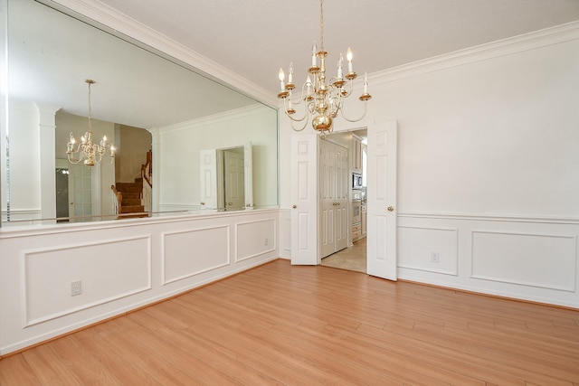 unfurnished dining area featuring a notable chandelier, light wood-type flooring, and crown molding