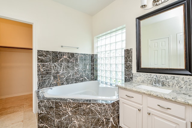 bathroom featuring tiled bath and vanity