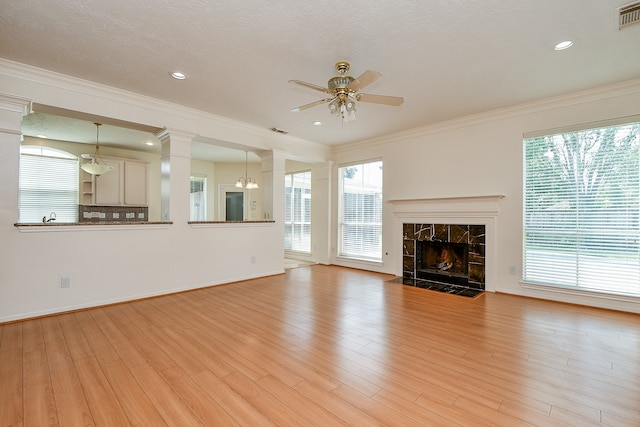 unfurnished living room with a tile fireplace, plenty of natural light, and crown molding