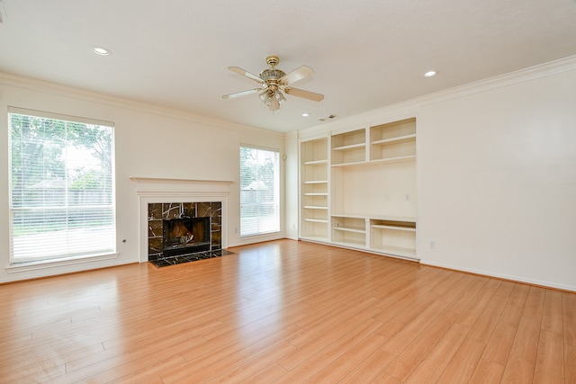 unfurnished living room featuring ceiling fan, a fireplace, light wood-type flooring, and ornamental molding