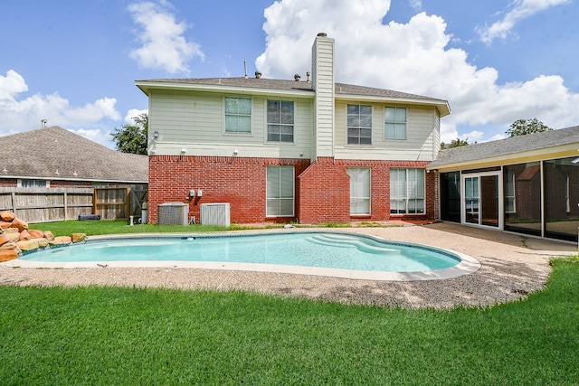 rear view of property featuring cooling unit, a fenced in pool, a yard, and a patio area