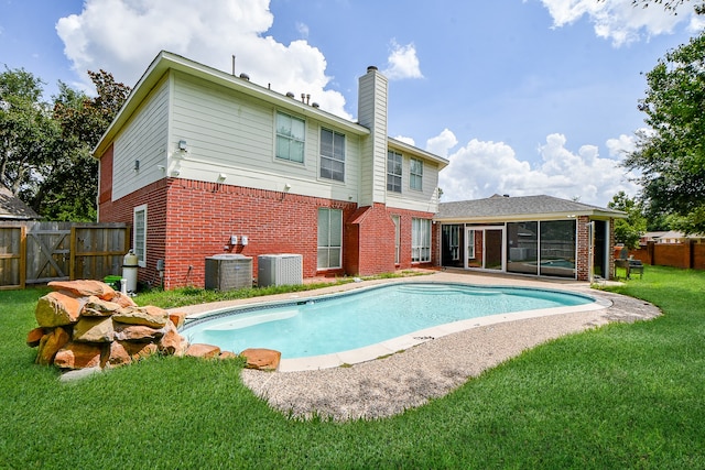 back of property with a yard, a sunroom, a fenced in pool, and central air condition unit