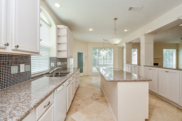 kitchen with light stone counters, pendant lighting, tasteful backsplash, a kitchen island, and dishwasher