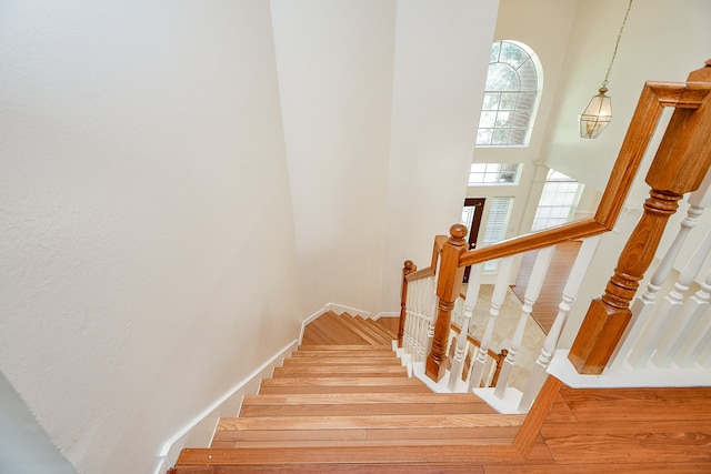 staircase featuring a towering ceiling and hardwood / wood-style floors