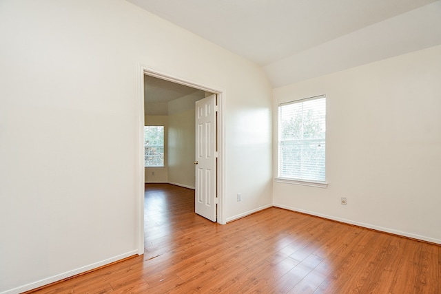 empty room with light wood-type flooring, vaulted ceiling, and a healthy amount of sunlight