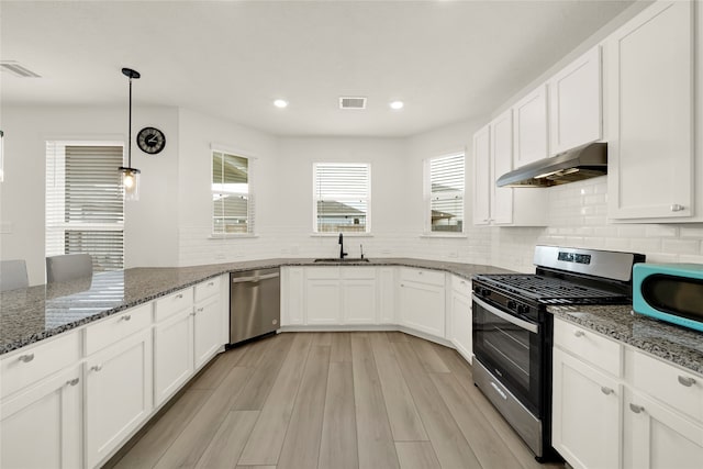 kitchen featuring light hardwood / wood-style flooring, stainless steel appliances, stone counters, and decorative light fixtures