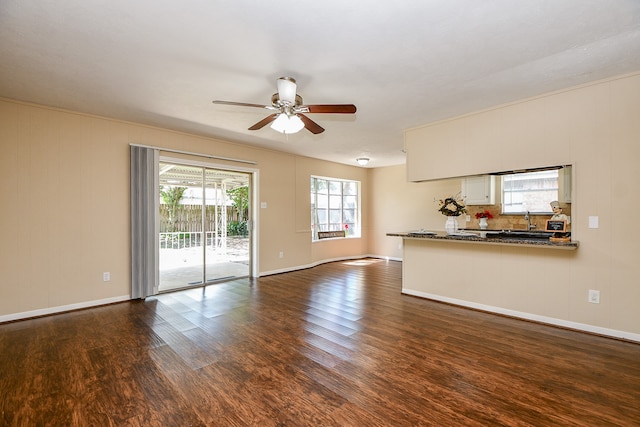 unfurnished living room featuring ceiling fan and dark hardwood / wood-style flooring