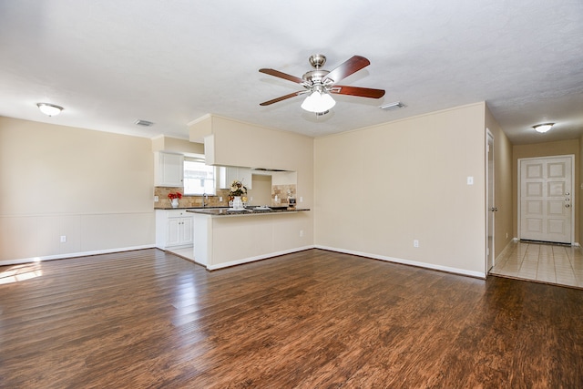 unfurnished living room featuring dark wood-type flooring, ceiling fan, and sink