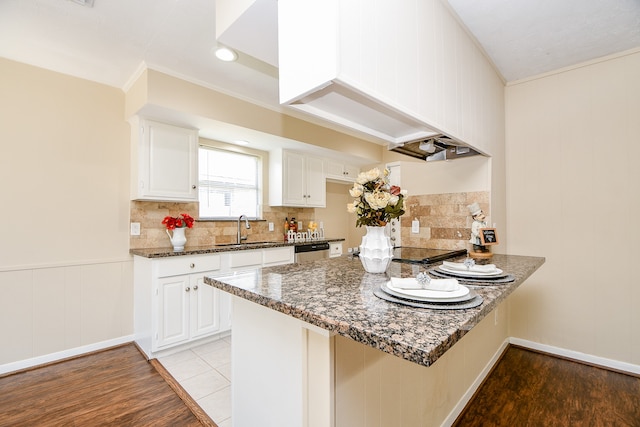 kitchen featuring kitchen peninsula, white cabinets, sink, and light wood-type flooring