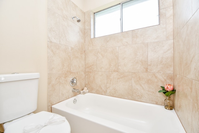 bathroom featuring a wealth of natural light, tiled shower / bath combo, and toilet