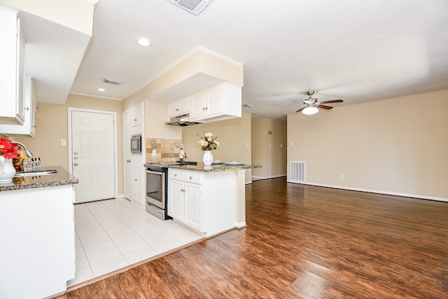 kitchen with light hardwood / wood-style floors, stainless steel appliances, dark stone counters, and white cabinets