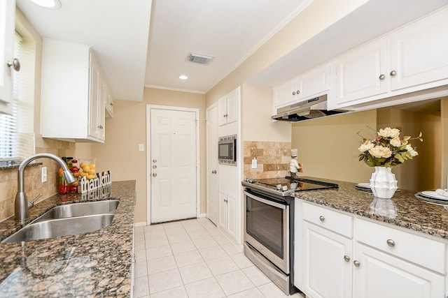 kitchen with white cabinets, tasteful backsplash, appliances with stainless steel finishes, dark stone countertops, and sink