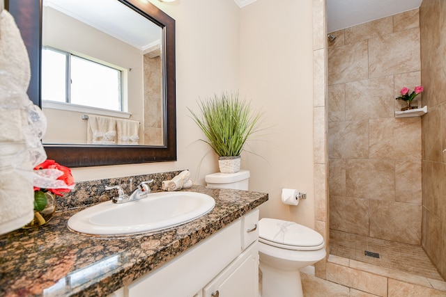 bathroom with tile patterned floors, toilet, crown molding, vanity, and a tile shower