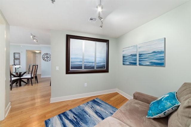 living area featuring crown molding, hardwood / wood-style flooring, and rail lighting