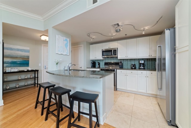 kitchen with stainless steel appliances, a breakfast bar, and white cabinets