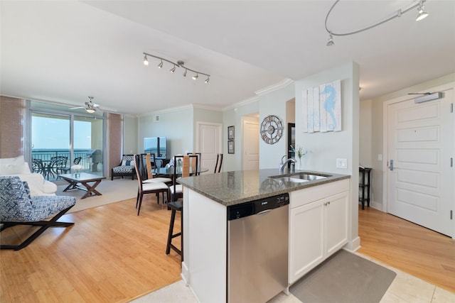 kitchen with sink, white cabinets, stainless steel dishwasher, dark stone counters, and light wood-type flooring