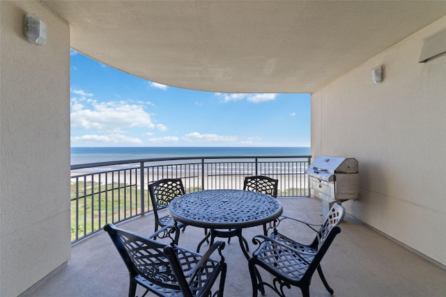 balcony featuring area for grilling, an outdoor kitchen, a beach view, and a water view