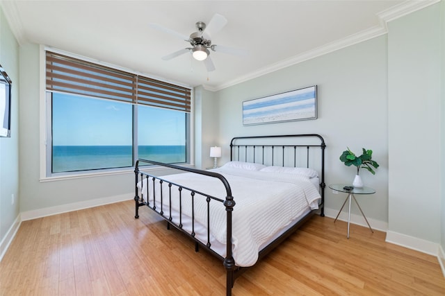 bedroom with a water view, ceiling fan, ornamental molding, and hardwood / wood-style flooring