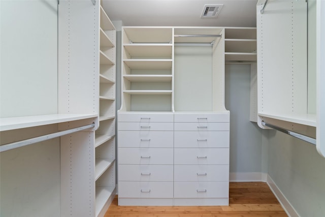 walk in closet with light hardwood / wood-style floors