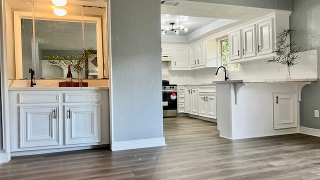 kitchen with decorative backsplash, dark hardwood / wood-style flooring, an inviting chandelier, white cabinetry, and stainless steel range