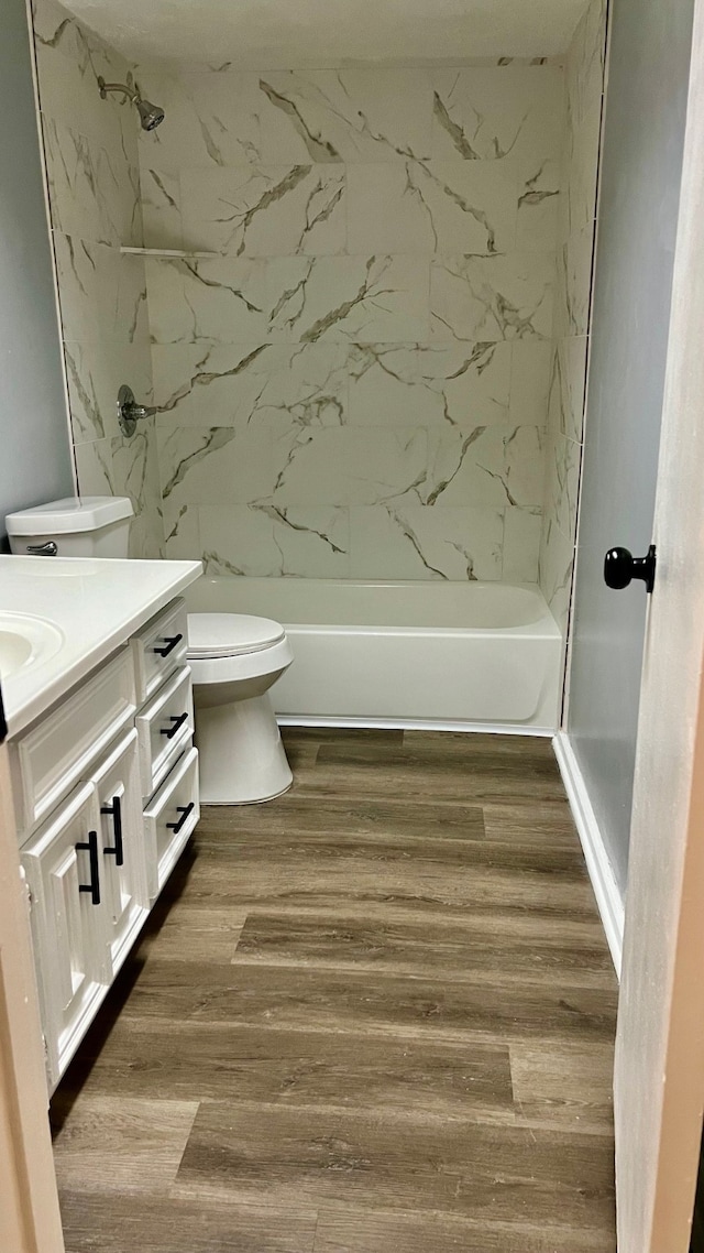 full bathroom featuring tiled shower / bath, vanity, hardwood / wood-style flooring, and toilet