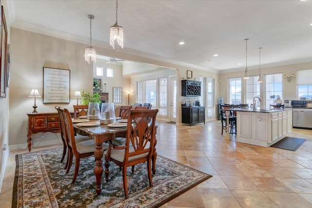 dining space with sink, ceiling fan with notable chandelier, ornamental molding, and a wealth of natural light