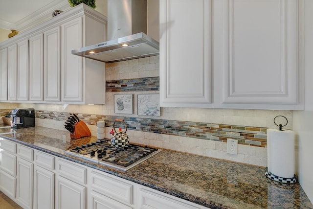 kitchen with decorative backsplash, dark stone countertops, white cabinetry, wall chimney exhaust hood, and stainless steel gas stovetop