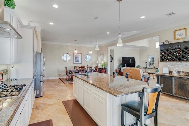 kitchen featuring white cabinets, decorative light fixtures, a kitchen island with sink, a kitchen breakfast bar, and stainless steel appliances