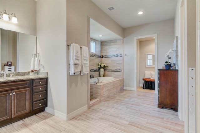 bathroom featuring vanity, hardwood / wood-style floors, and plus walk in shower