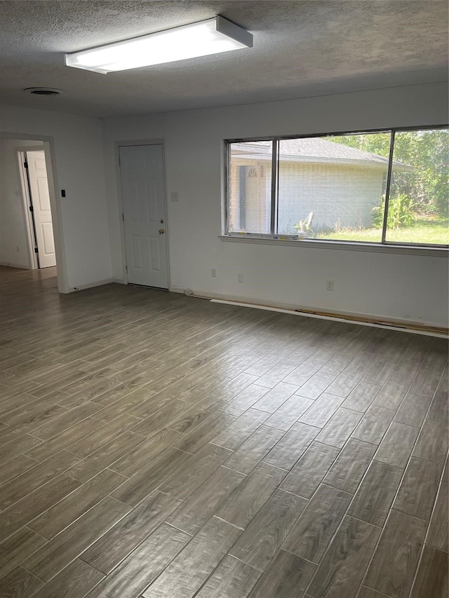 spare room with a textured ceiling and hardwood / wood-style floors