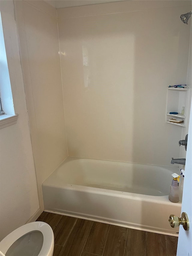 bathroom featuring shower / bath combination, hardwood / wood-style floors, and toilet