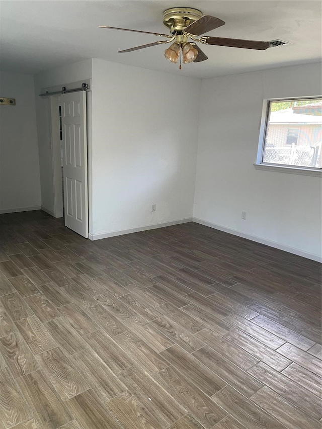 unfurnished room featuring ceiling fan, hardwood / wood-style floors, and a barn door