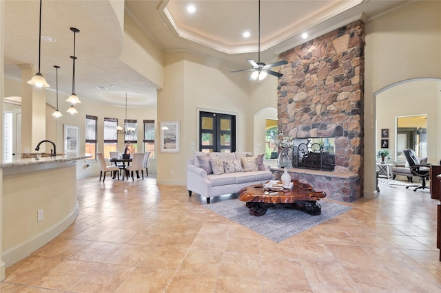 tiled living room featuring crown molding, a fireplace, a raised ceiling, and a high ceiling