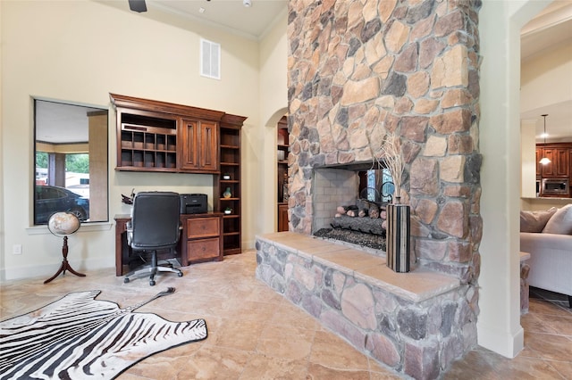 home office with crown molding, a towering ceiling, and a fireplace