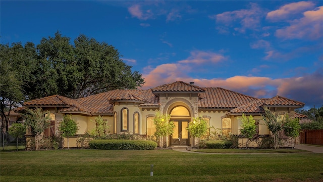 mediterranean / spanish home with french doors and a lawn