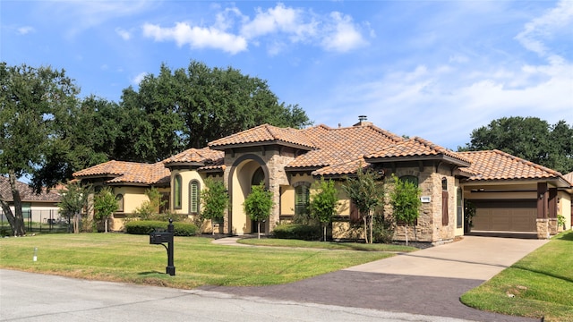 mediterranean / spanish home with a garage and a front lawn