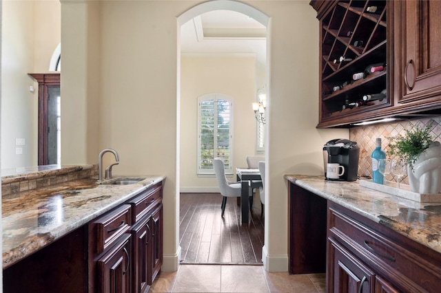 kitchen with tasteful backsplash, sink, dark brown cabinetry, and light stone counters