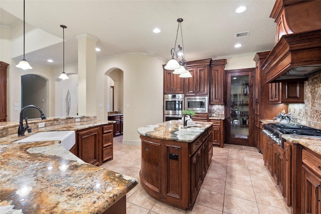 kitchen featuring a large island with sink, hanging light fixtures, sink, and stainless steel appliances