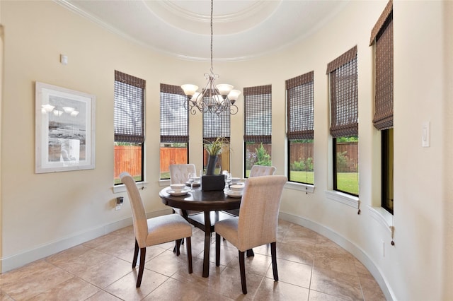 tiled dining space with a raised ceiling, crown molding, and a chandelier