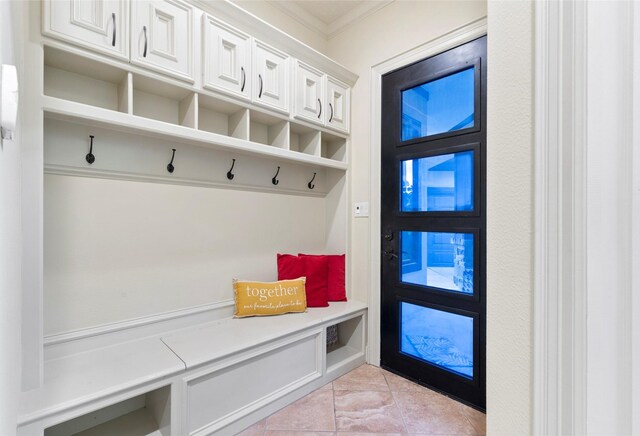 mudroom featuring ornamental molding and light tile patterned floors