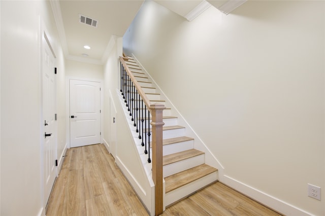 stairway featuring wood-type flooring and crown molding