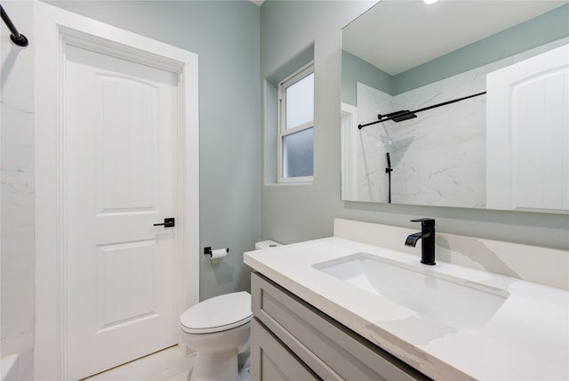 bathroom featuring a tile shower, vanity, and toilet