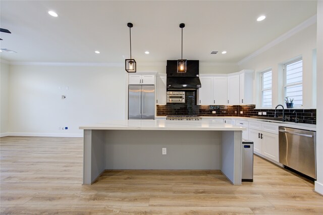 kitchen with pendant lighting, light hardwood / wood-style floors, a center island, custom exhaust hood, and appliances with stainless steel finishes