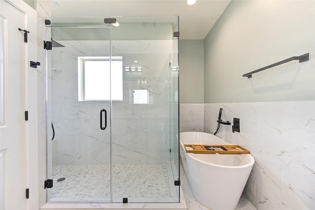 bathroom featuring shower with separate bathtub and tile walls