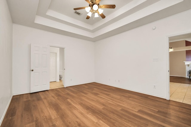 spare room featuring a raised ceiling, ceiling fan, and wood-type flooring