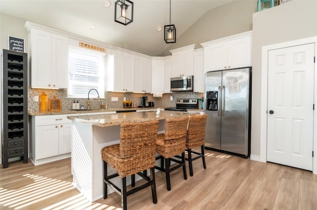 kitchen featuring stainless steel appliances, white cabinetry, a kitchen island, and tasteful backsplash