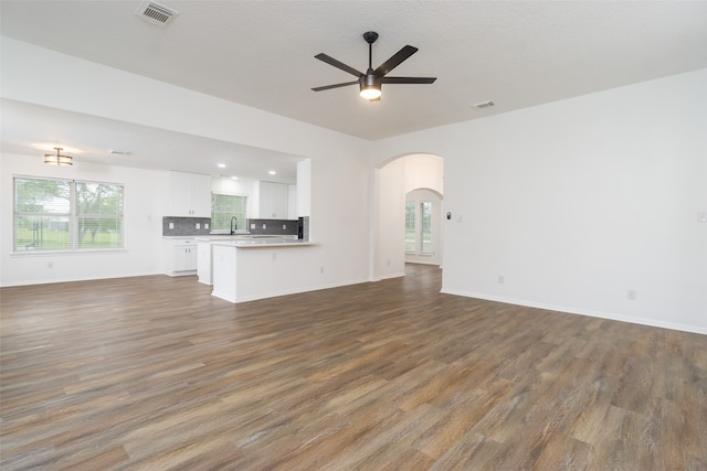 unfurnished living room with a textured ceiling, dark hardwood / wood-style flooring, ceiling fan, and sink