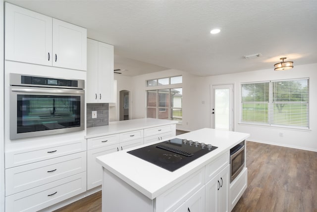 kitchen with stainless steel appliances, white cabinetry, plenty of natural light, and dark wood-type flooring