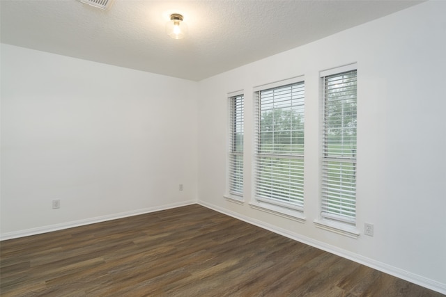 spare room with a textured ceiling and dark wood-type flooring